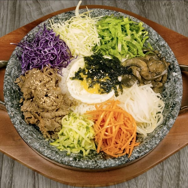 SSAMJANG Korean BBQ's colorful bibimbap in a stone bowl, featuring beef, egg, and various vegetables.