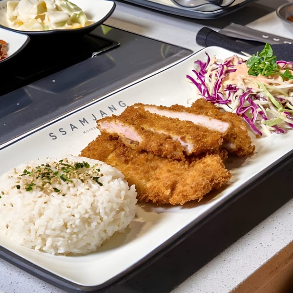 Crispy fried pork cutlets, white rice with herbs, and a side salad on a white plate.