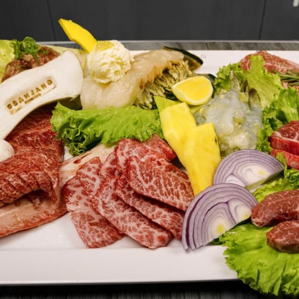 A platter of raw Korean BBQ meats, shrimp, onions, pineapple, and lettuce from SSAMJANG.