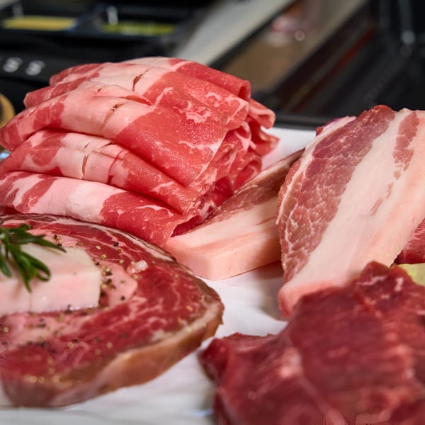 Assortment of fresh, raw Korean BBQ meats, including thinly sliced beef and pork belly.