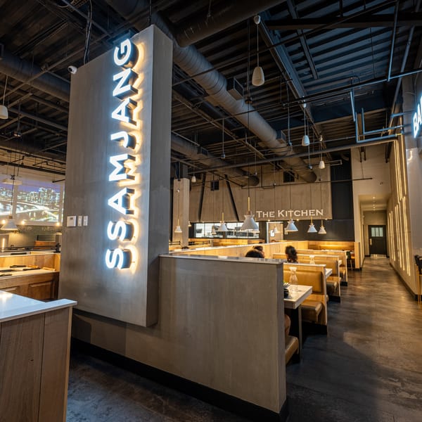 Interior of SSAMJANG Korean BBQ, featuring a neon sign, modern decor, and booth seating.