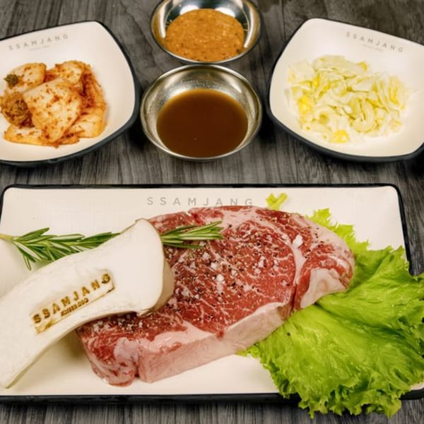 SSAMJANG Korean BBQ raw beef with mushroom, rosemary, lettuce, kimchi, and dipping sauces.
