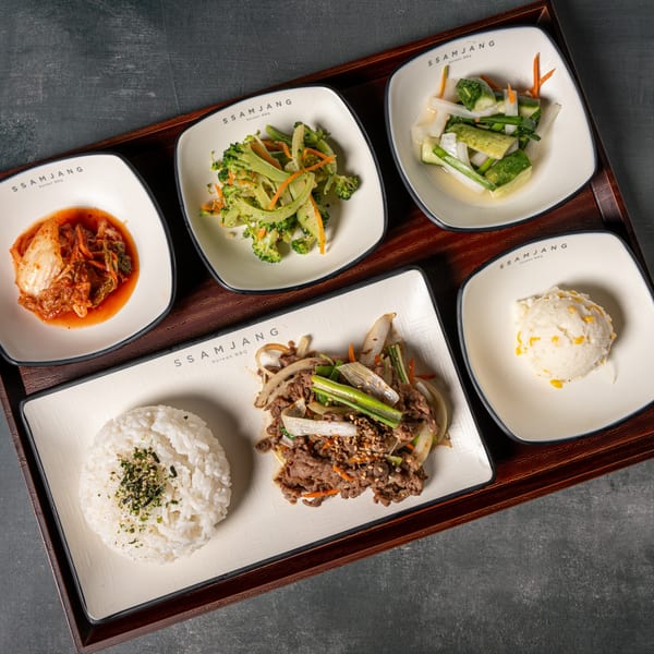 A Korean BBQ meal with bulgogi, rice, kimchi, broccoli, pickled vegetables, and mashed potatoes.
